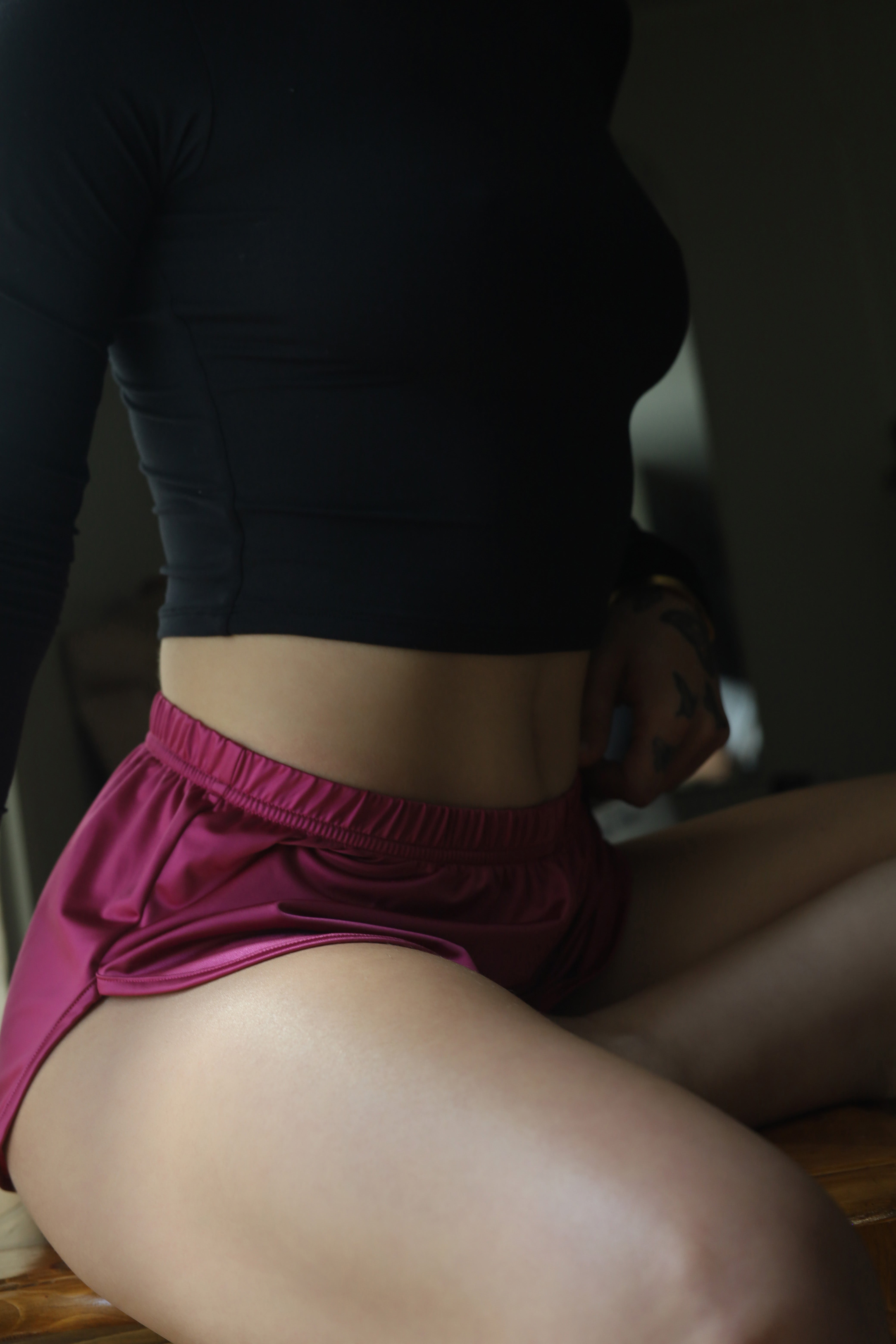 Purple satin shortie with elastic waistband shown under a dark long-sleeve top
