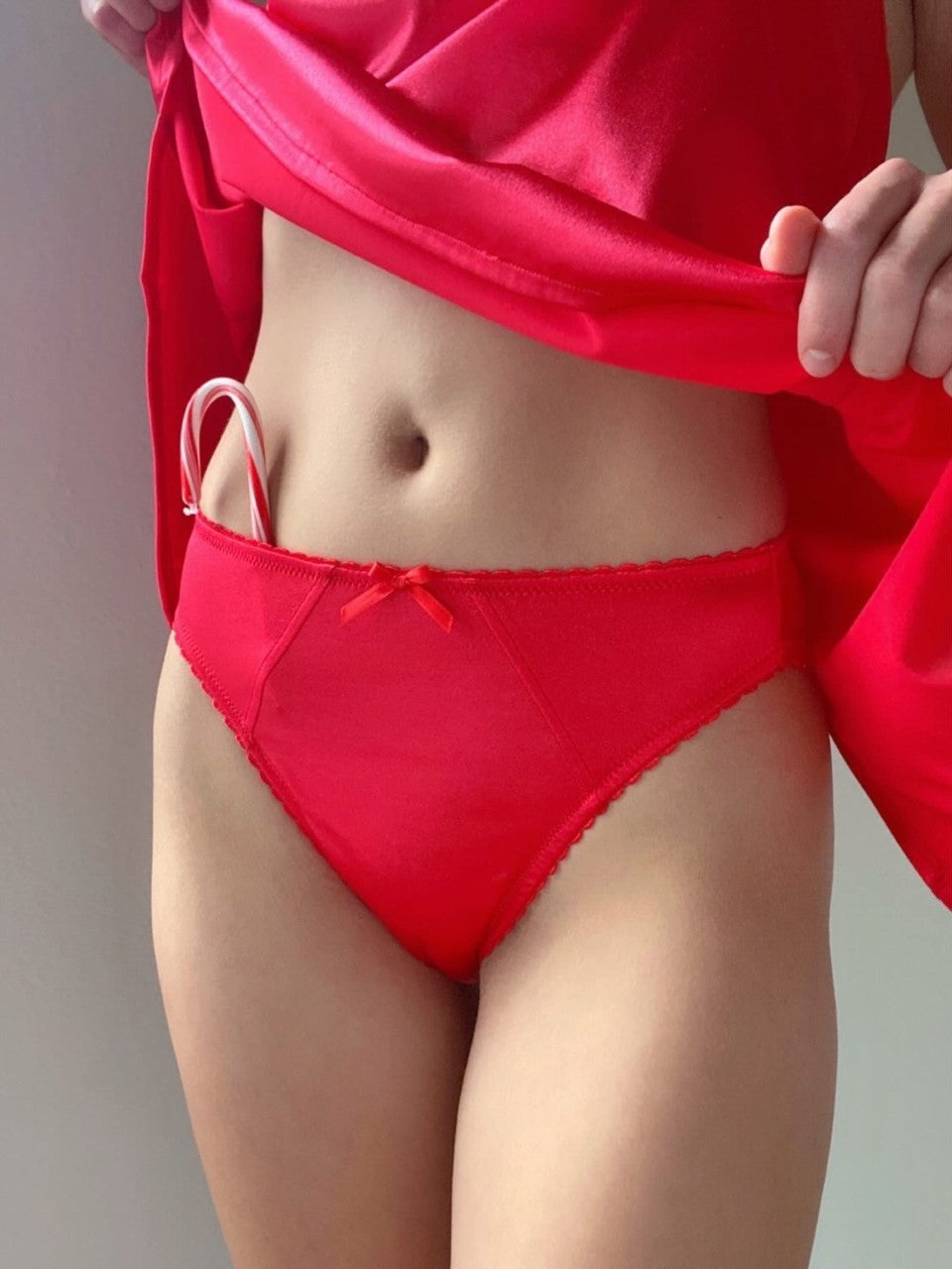 Red satin hipster panties with lace-trim leg openings and center bow detail.