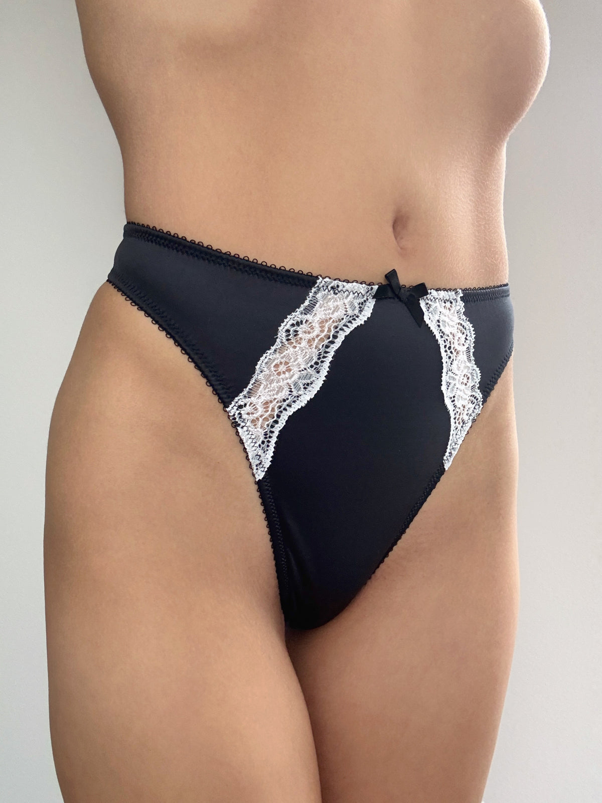 Midnight black thong panties with white lace side panels and center bow