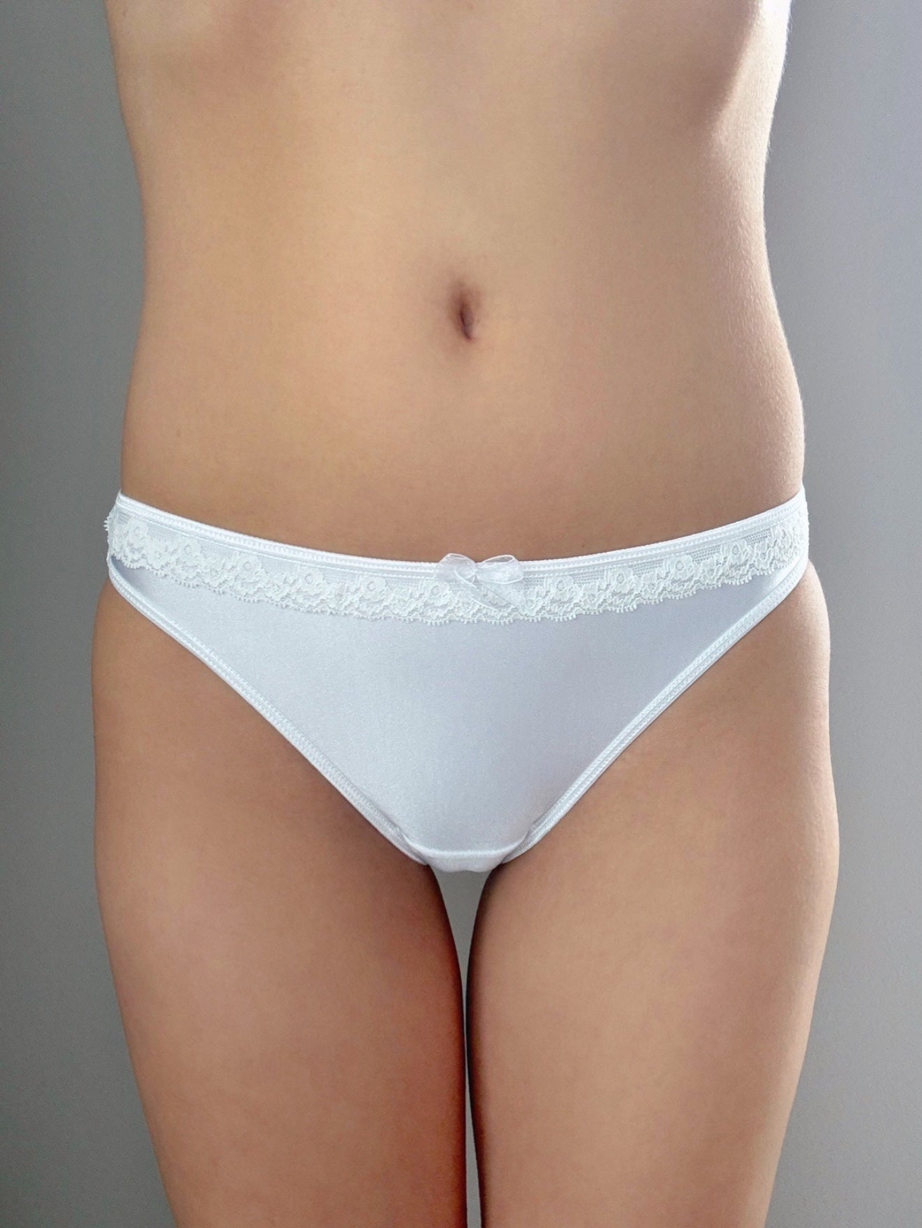 Pure white lace-trim mini panties, front view with small bow