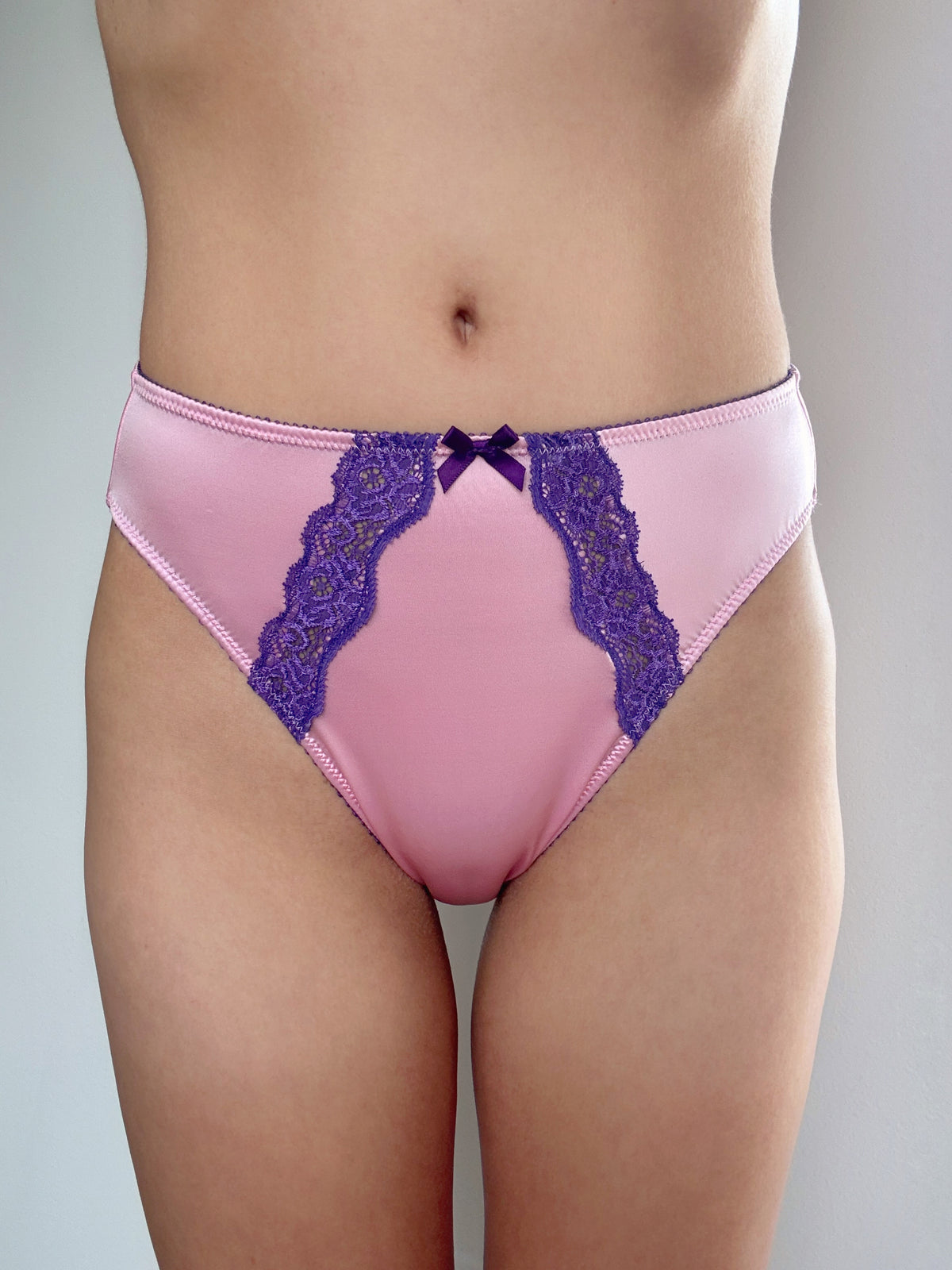 Pink satin panties with purple lace panels and bow detail at waistband